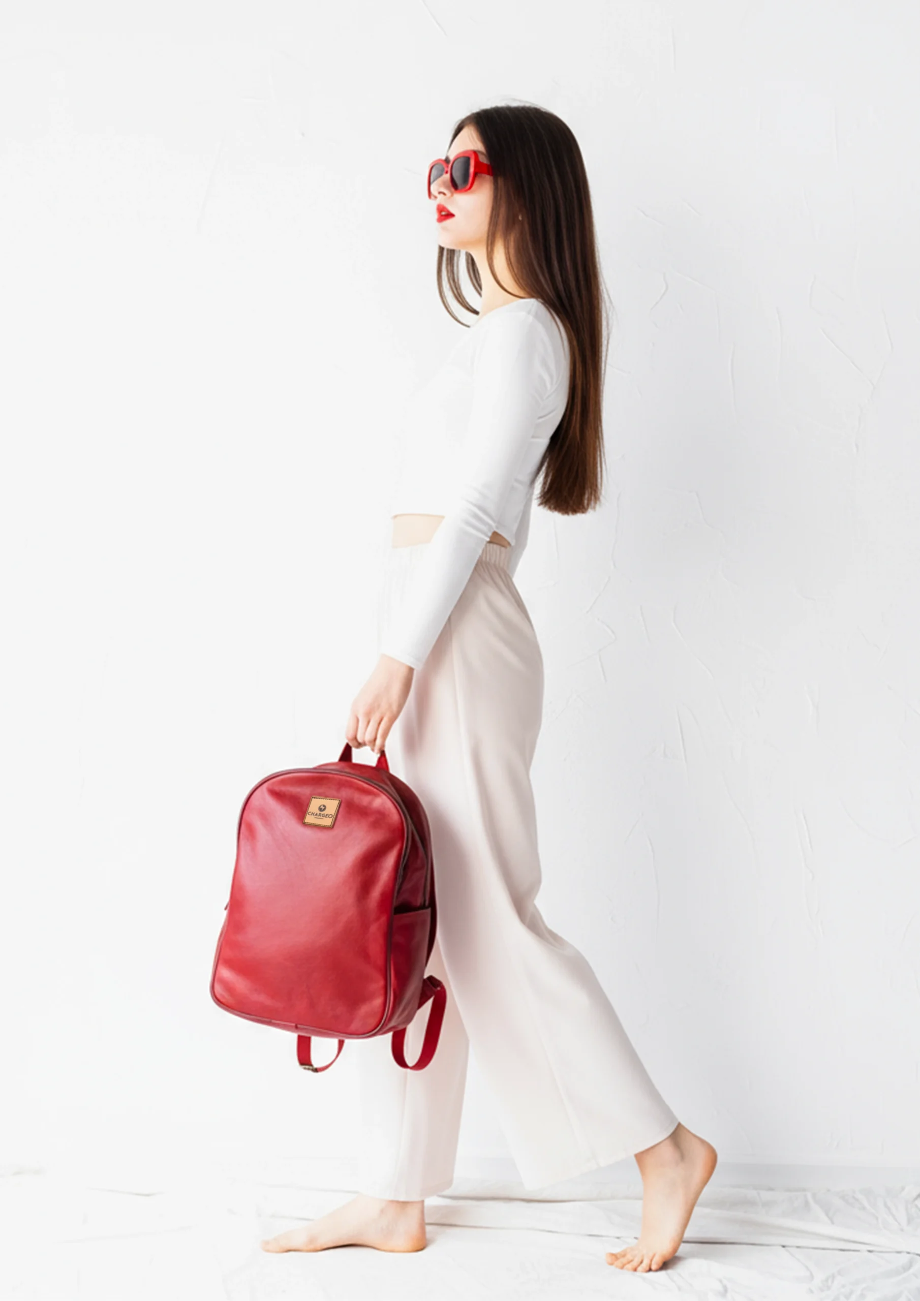 A woman holding the CHARGEO Constantia RedRuby leather backpack as a chic accessory
