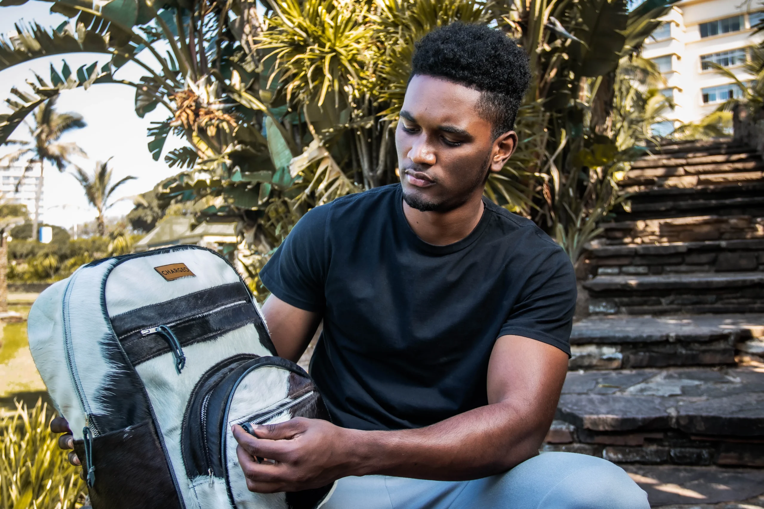 Man sitting down and looking at the details of a CHARGEO Zulu Treasure leather backpack