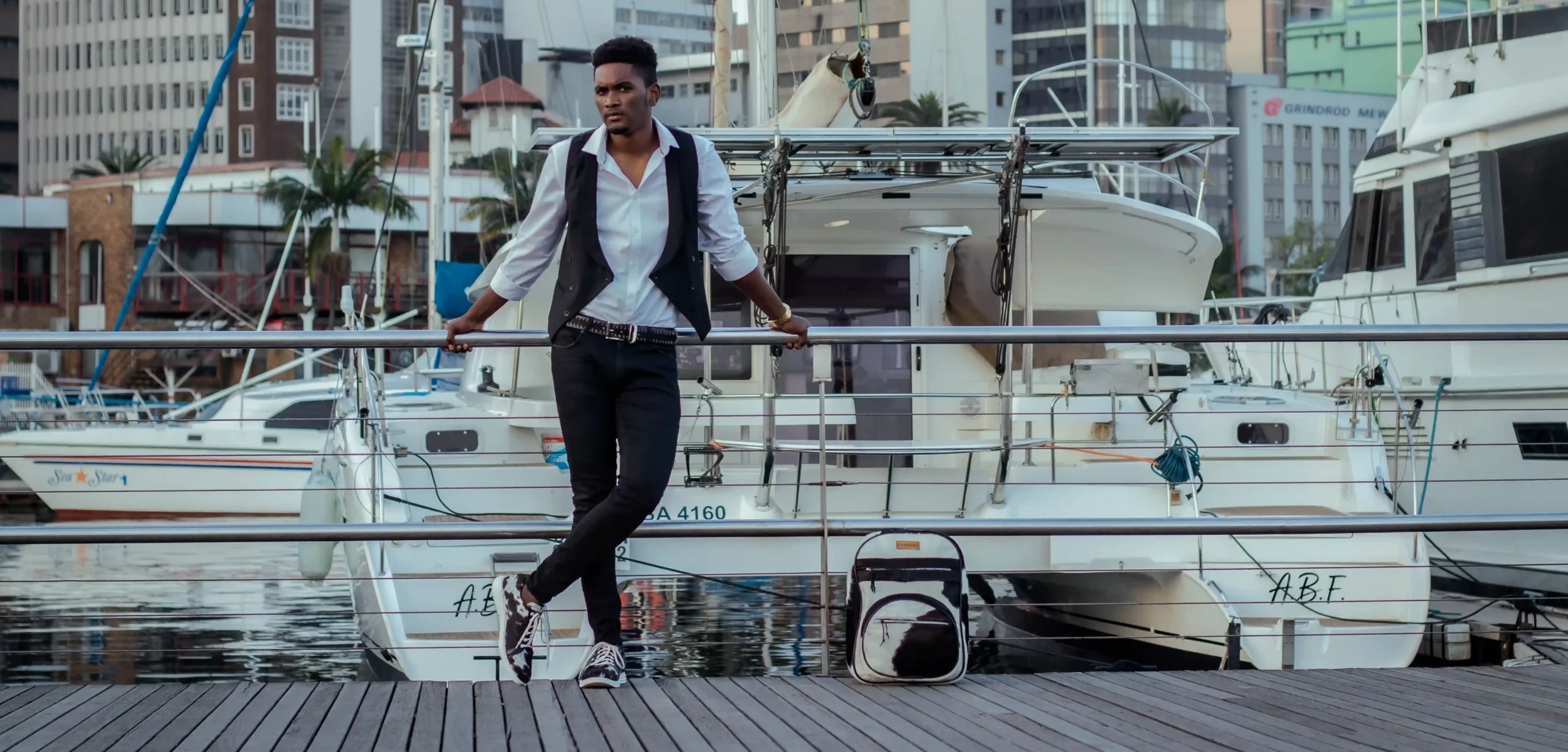 Model wearing Zulu Tressure sneakers and Belt next to the Zulu Tressure Backpack