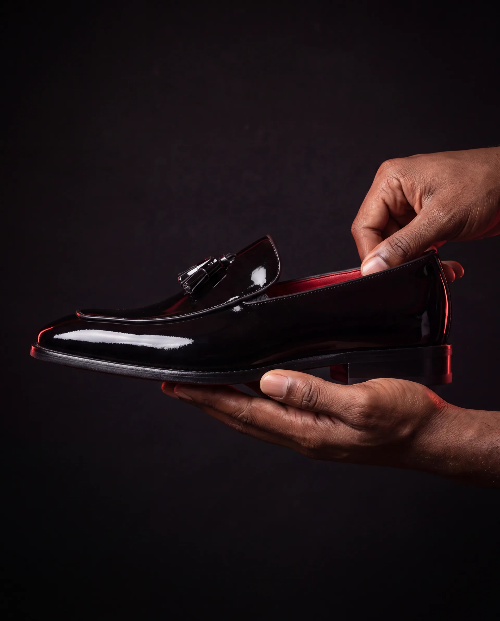Hands presenting the CHARGEO black patent leather tassel loafer
