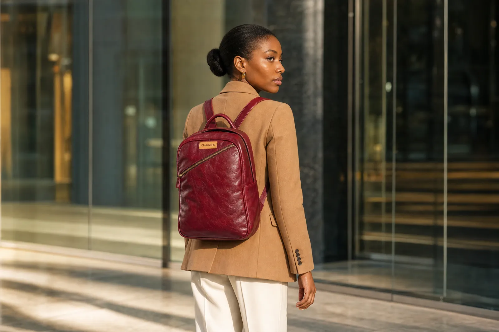 Woman in a camel blazer in an office lobby in Sandton wearing a CHARGEO Pretoria Leather Backpack for Women