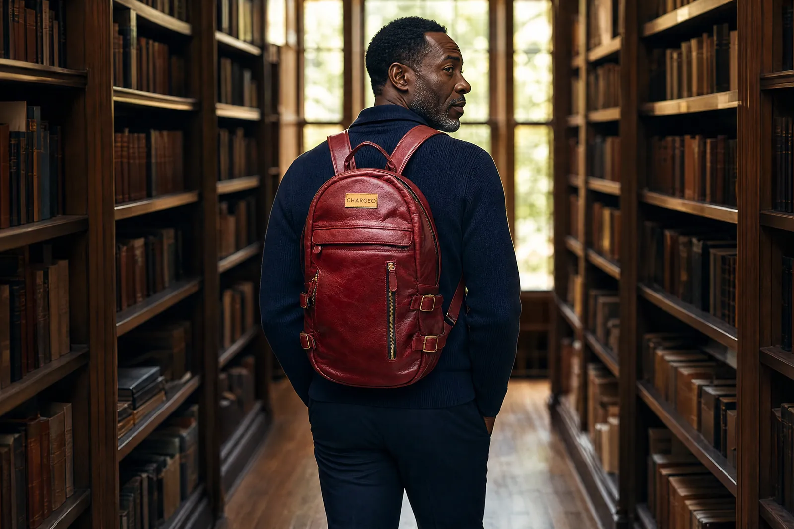 Man in a library wearing a CHARGEO RedRuby leather backpack