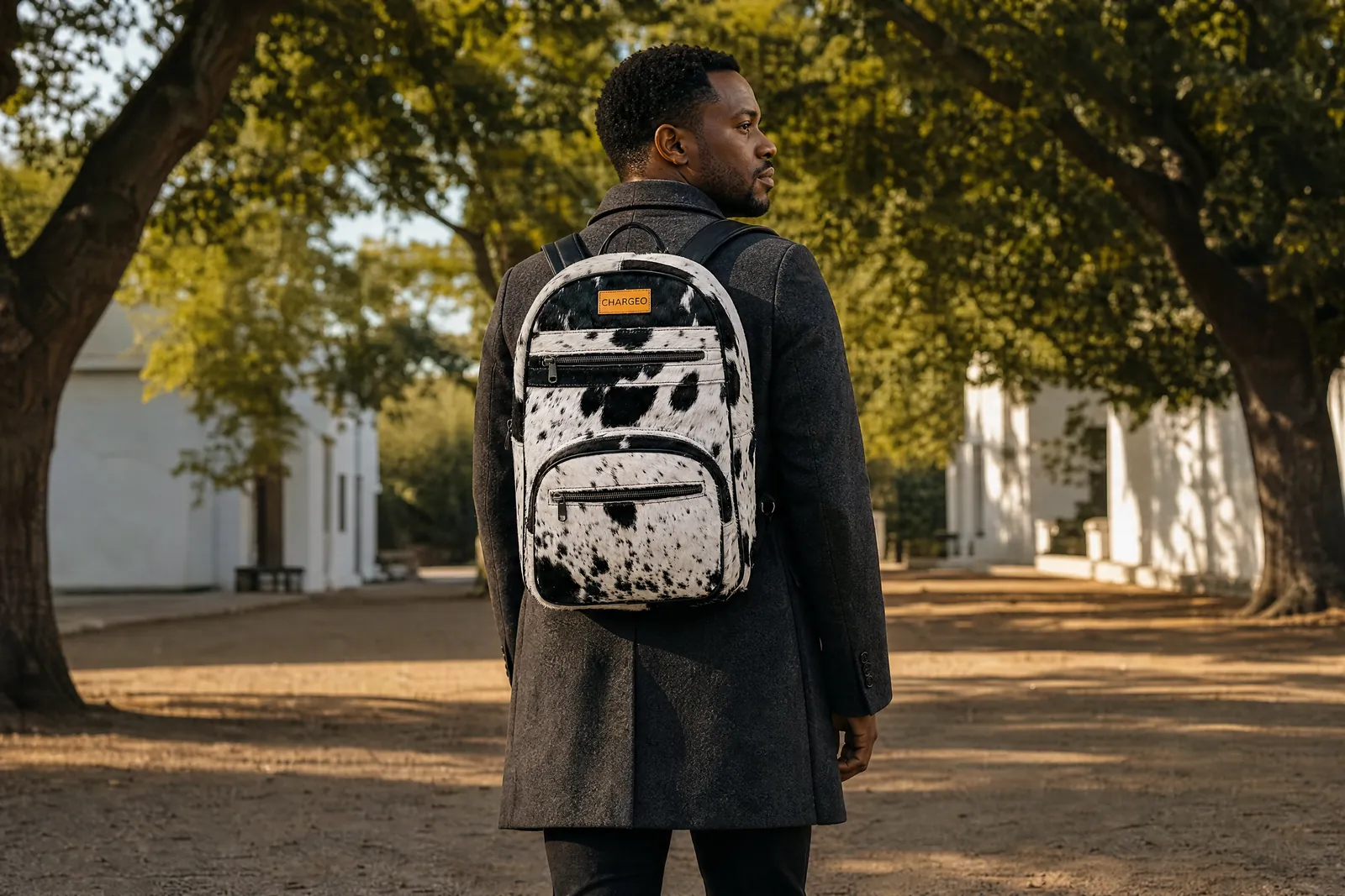 Man in a square with oak trees in Stellenbosch wearing a CHARGEO Zulu Treasure Nguni hide leather backpack