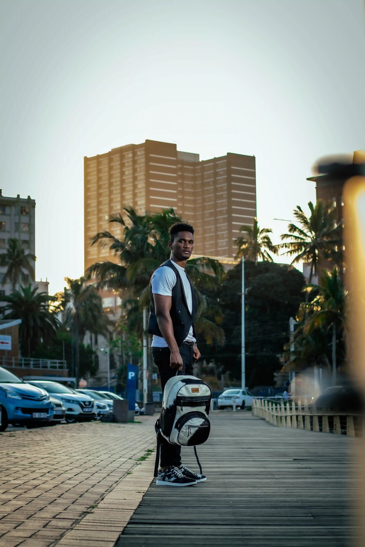 A man in a white T-shirt and waistcoat standing at the marina rail with the CHARGEO black and white hide backpack, August 2023