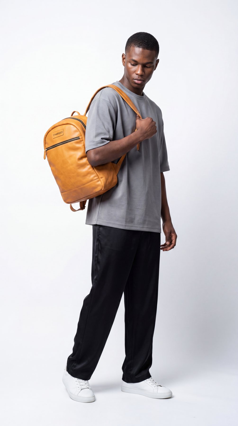 A man in the studio wearing a CHARGEO tan leather backpack over one shoulder