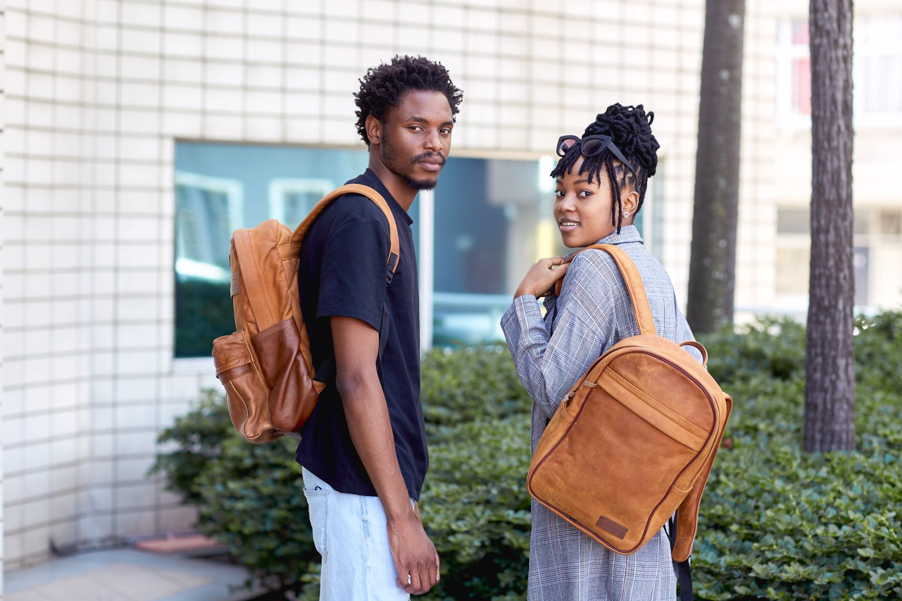 Two models with CHARGEO tan leather backpacks outside an old building in Durban, January 2022
